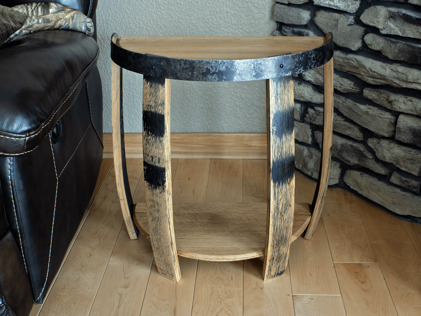 Front view of a whiskey barrel half end table featuring weathered wood staves with original barrel markings and a curved metal band, evoking a rustic yet elegant charm in a natural living space setting.